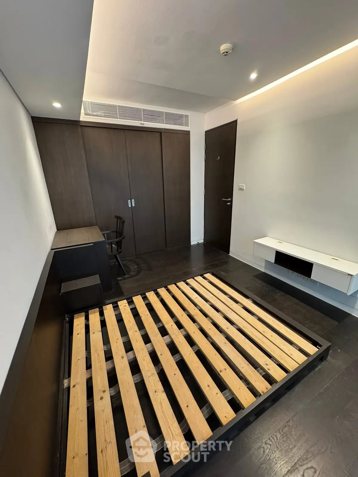 Modern bedroom with dark wood flooring and built-in wardrobe