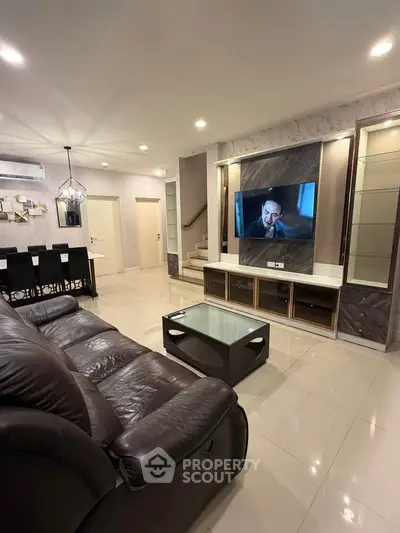 Spacious modern living room with leather sofa and large TV, perfect for family gatherings.