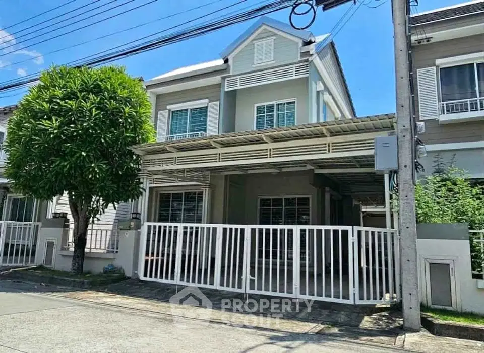 Charming two-story townhouse with gated front yard and lush greenery, perfect for family living.