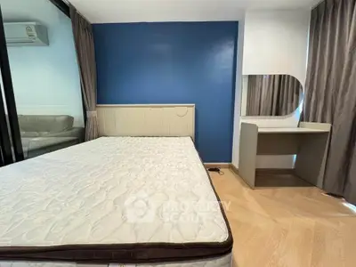 Modern bedroom with blue accent wall and stylish furniture in a cozy apartment.