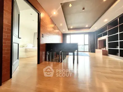 Spacious modern living room with wooden flooring and large windows offering natural light.