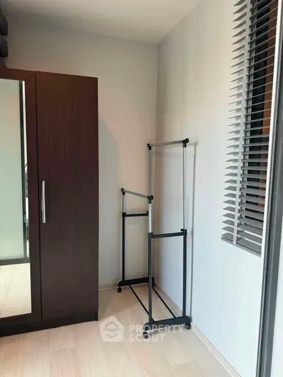 Modern minimalist bedroom with wardrobe and clothes rack, featuring sleek design and natural light.