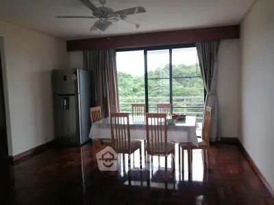 Spacious dining area with large window and scenic view, featuring elegant wooden flooring and modern ceiling fan.