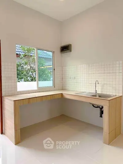 Modern kitchen with wooden countertops and tiled backsplash, featuring a sleek sink and large window.