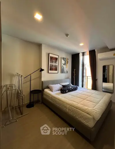 Modern bedroom with stylish decor and natural light, featuring a cozy bed and contemporary artwork.