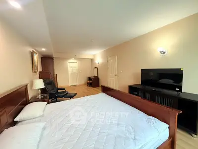 Spacious bedroom with wooden furniture and modern TV setup
