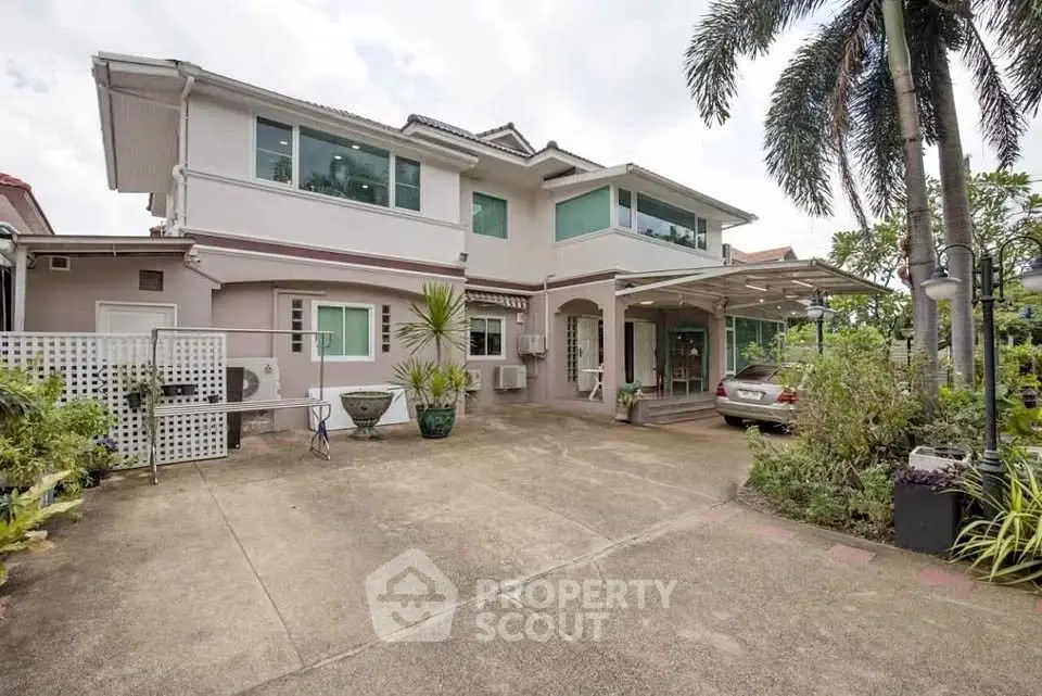 Spacious two-story house with lush garden and carport in a serene neighborhood.
