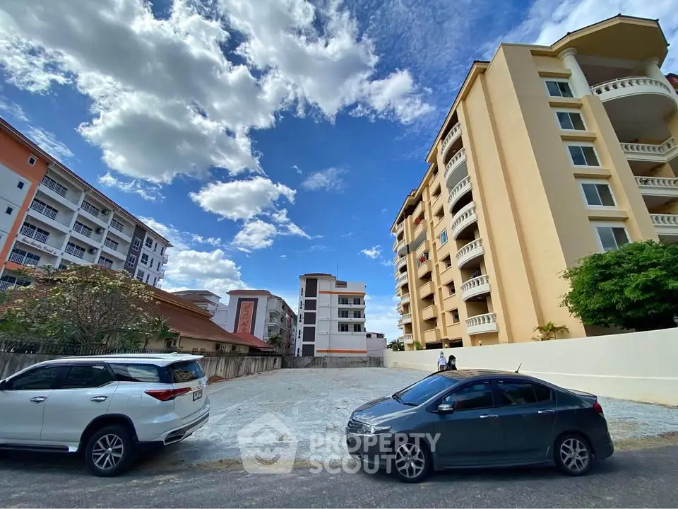 Spacious urban lot surrounded by modern apartment buildings under a vibrant blue sky.