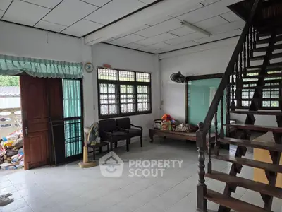 Spacious living room with wooden staircase and ample natural light, perfect for family gatherings.
