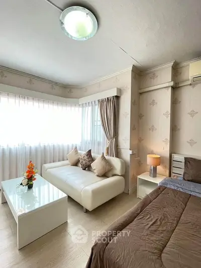 Cozy bedroom with elegant decor and natural light, featuring a stylish sofa and modern furnishings.