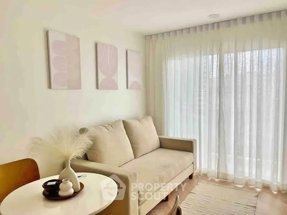 Cozy living room with soft beige sofa, sheer curtains, and modern wall art.