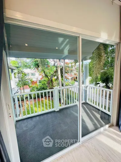 Spacious balcony with sliding glass doors and lush garden view