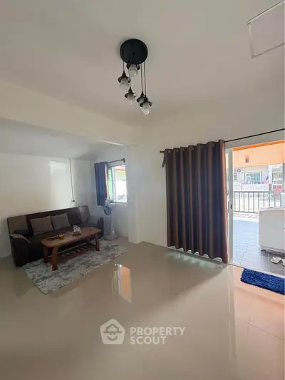 Spacious living room with modern decor and large windows opening to a balcony, perfect for relaxation.