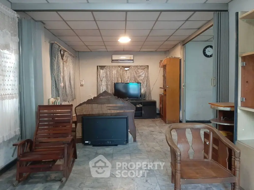 Spacious living room with vintage wooden furniture and modern TV setup.