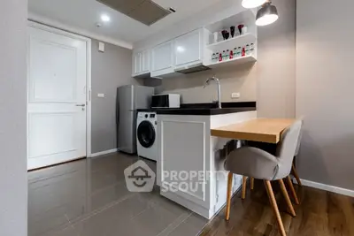 Modern kitchen with washing machine and sleek cabinetry in compact apartment