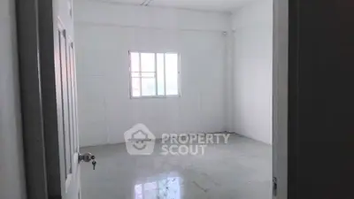 Spacious empty room with large window and white walls, perfect for customization.