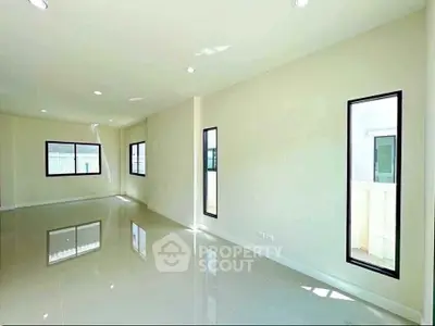 Spacious sunlit living room with modern windows and glossy floors in a contemporary home.