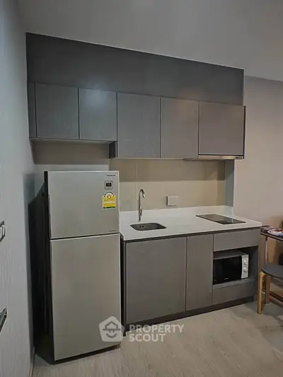 Modern compact kitchen with sleek cabinetry and integrated appliances in a stylish apartment.