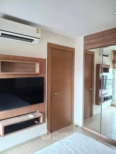 Modern bedroom with wall-mounted TV and mirrored wardrobe in a stylish apartment.