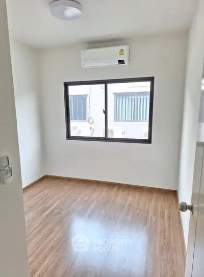 Bright empty room with wooden flooring and air conditioning, perfect for customization.