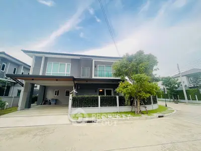 Modern two-story house with spacious driveway and lush greenery.
