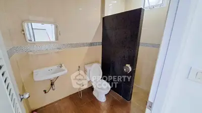 Modern bathroom with sleek design and tiled walls, featuring a toilet and sink.