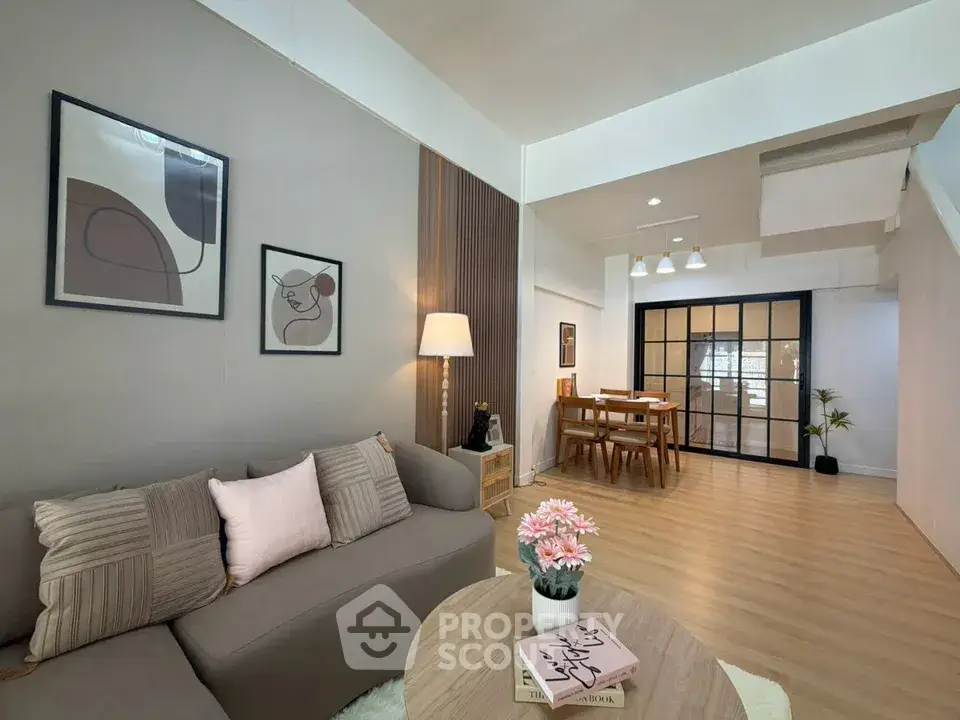 Modern living room with stylish decor and open dining area, featuring cozy seating and elegant lighting.