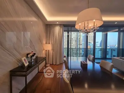 Luxurious dining room with elegant chandelier and city view balcony in high-rise apartment.