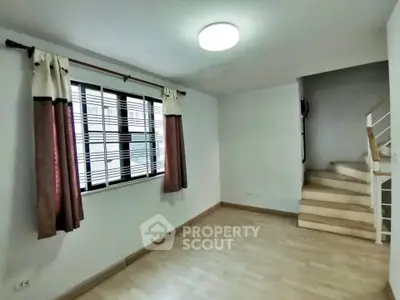 Cozy living room with staircase and natural light from window
