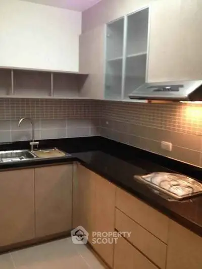 Modern kitchen with sleek cabinetry and black countertops in a contemporary apartment.