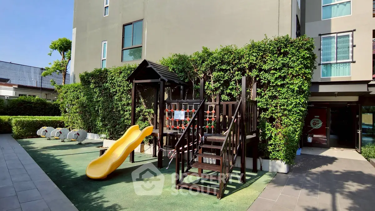 Modern apartment building with children's playground and lush greenery.