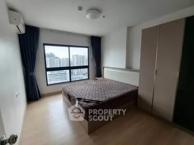 Spacious bedroom with large window offering stunning city views in modern apartment.