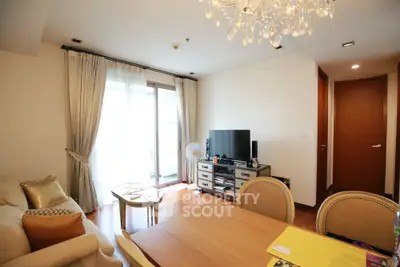 Elegant living room with chandelier, large window, and stylish furniture in modern apartment.