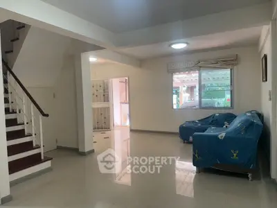 Spacious living room with staircase and large window, perfect for family gatherings.