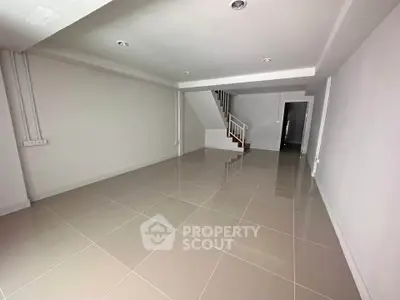 Spacious modern living room with sleek tile flooring and staircase, perfect for contemporary living.