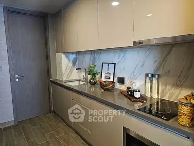 Modern kitchen with sleek cabinetry and marble backsplash in luxury apartment.