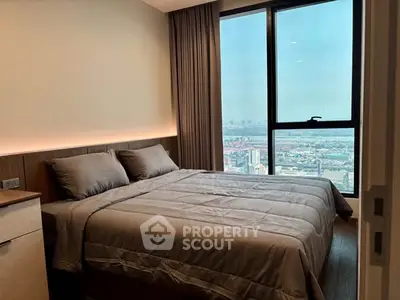 Luxurious bedroom with stunning city view from high-rise apartment window.