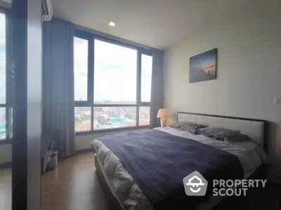 Spacious bedroom with large window offering stunning city views and modern decor.