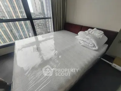 Modern bedroom with large window and city view, featuring a neatly made bed.