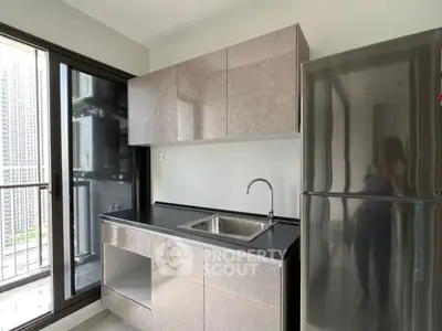 Modern kitchen with sleek cabinets and stainless steel fridge in high-rise apartment.