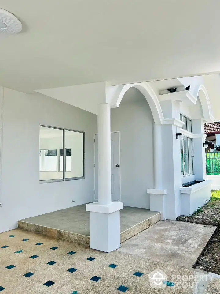 Charming home exterior with elegant white arches and columns, featuring a spacious covered porch and large windows for ample natural light.