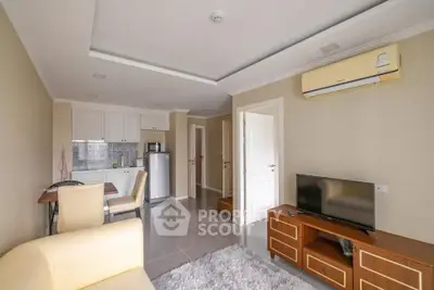 Modern living room with open kitchen, featuring sleek furniture and air conditioning.