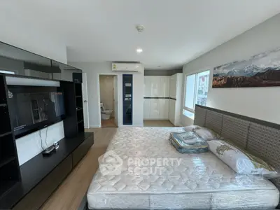 Modern bedroom with large bed, built-in wardrobe, and wall-mounted TV in a bright apartment.
