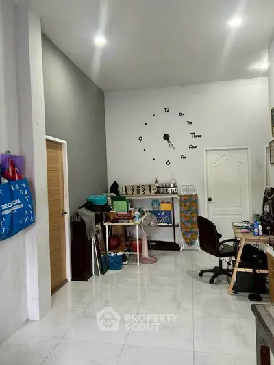 Spacious room with modern decor and wall clock, ideal for home office or study area.