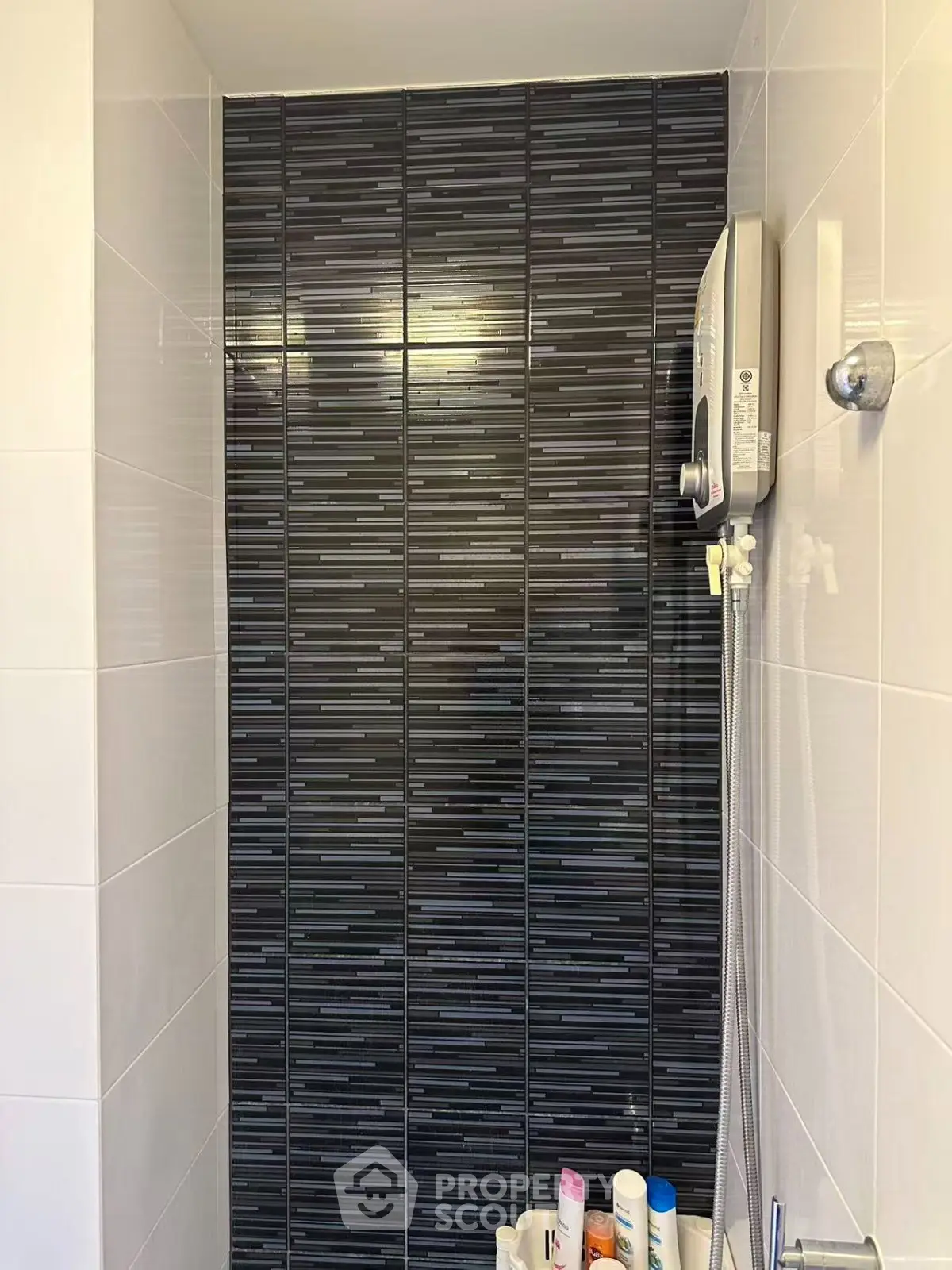 Modern bathroom shower with sleek black tile design and wall-mounted water heater.