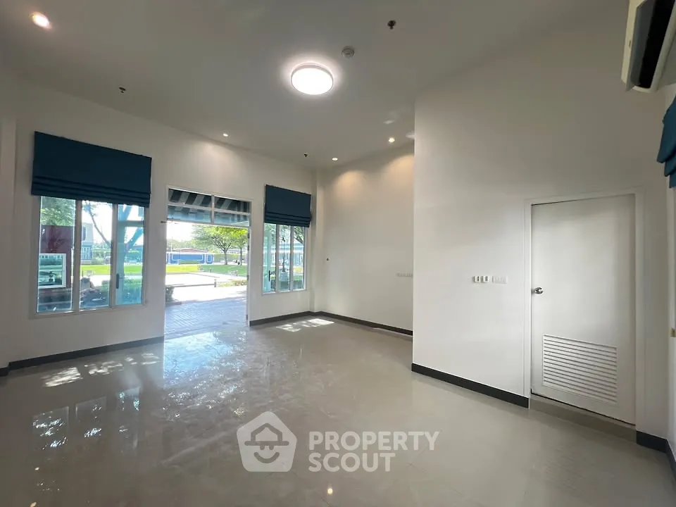 Spacious empty room with large windows and modern lighting, perfect for customization.