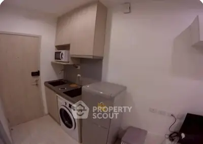Compact kitchen with modern appliances including washing machine and microwave, ideal for urban living.