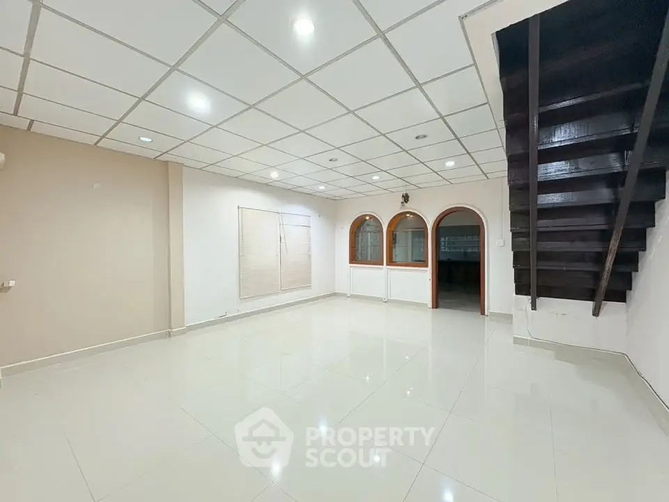 Spacious living room with modern ceiling and staircase, perfect for family gatherings.