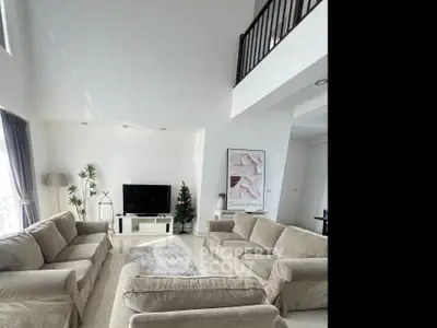 Spacious living room with high ceiling and modern decor, featuring cozy sofas and a sleek entertainment center.