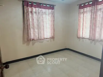 Spacious empty bedroom with tiled floor and floral curtains